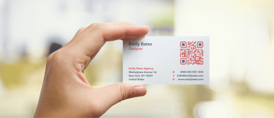 Main tenant une carte de visite ave un code QR rouge et noir imprimé en haut à droite.