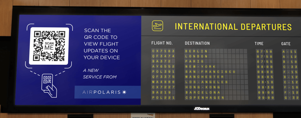 Code QR sur le tableau des départs d’un aéroport encourageant le public à scanner le code pour afficher sur smartphone les informations récentes concernant leur vol.