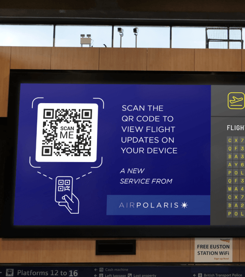 Code QR sur le tableau des départs d’un aéroport encourageant le public à scanner le code pour afficher sur smartphone les informations récentes concernant leur vol.