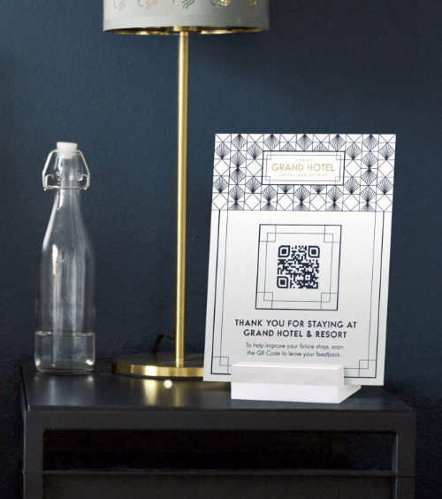 Cavalier de table dans une chambre d’hôtel avec code QR vers un formulaire de satisfaction.