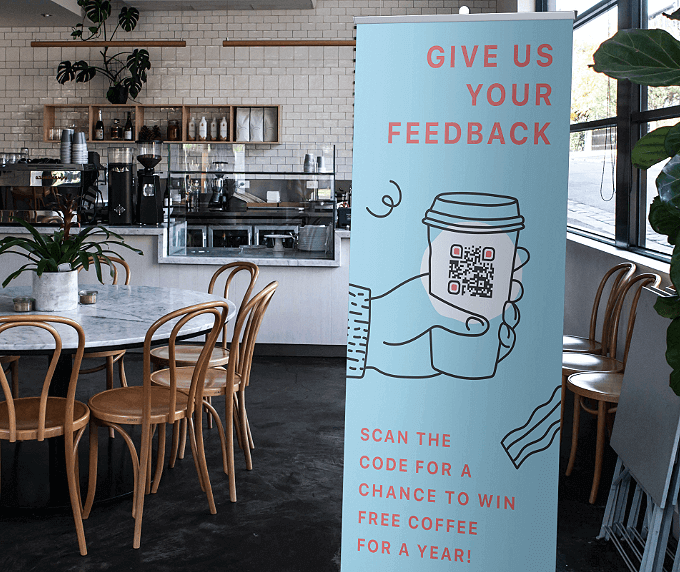 Kakemono dans un café avec code QR vers un jeu permettant de gagner des cafés gratuits.