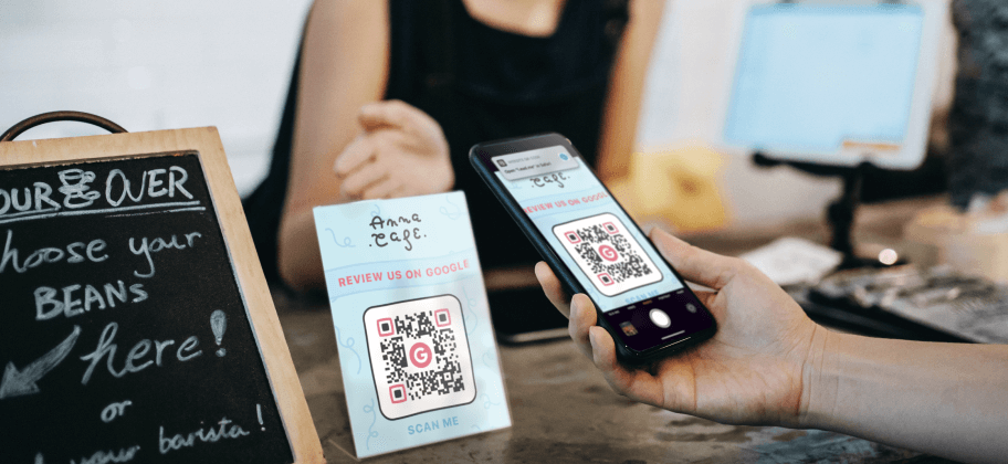 Main tenant un smartphone dirigé vers un code QR Avis Google dans un commerce.